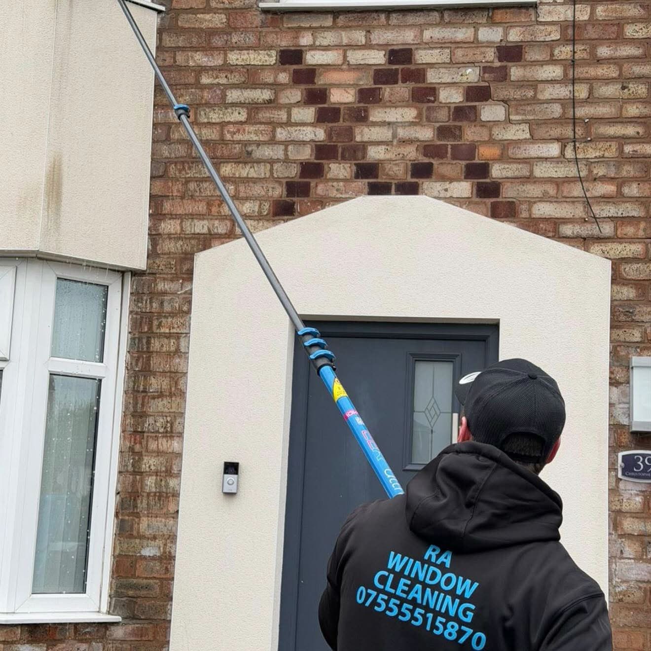 RA Window Cleaning operative cleaning a house